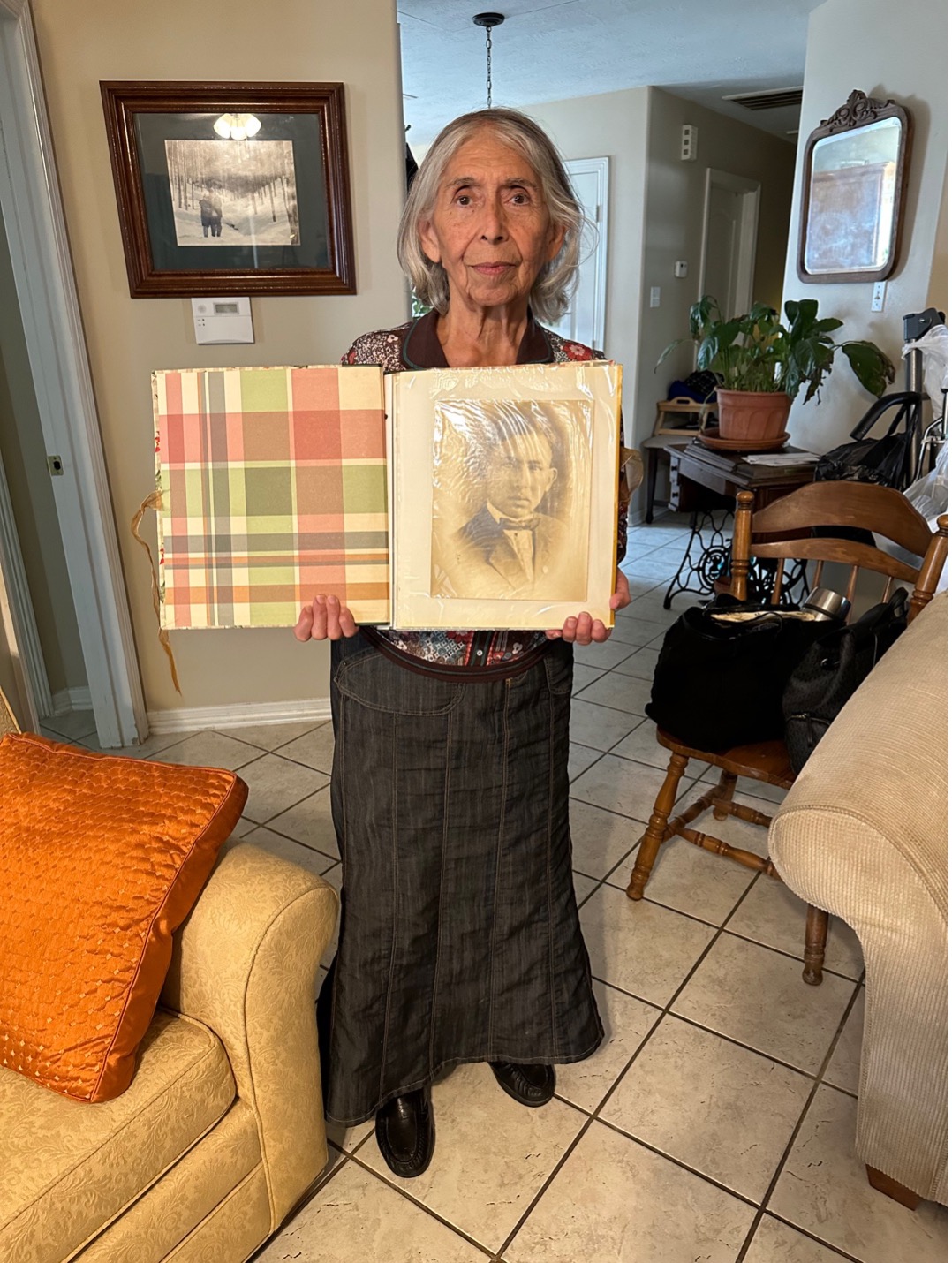 An old person holding a picture in a room

Description automatically generated